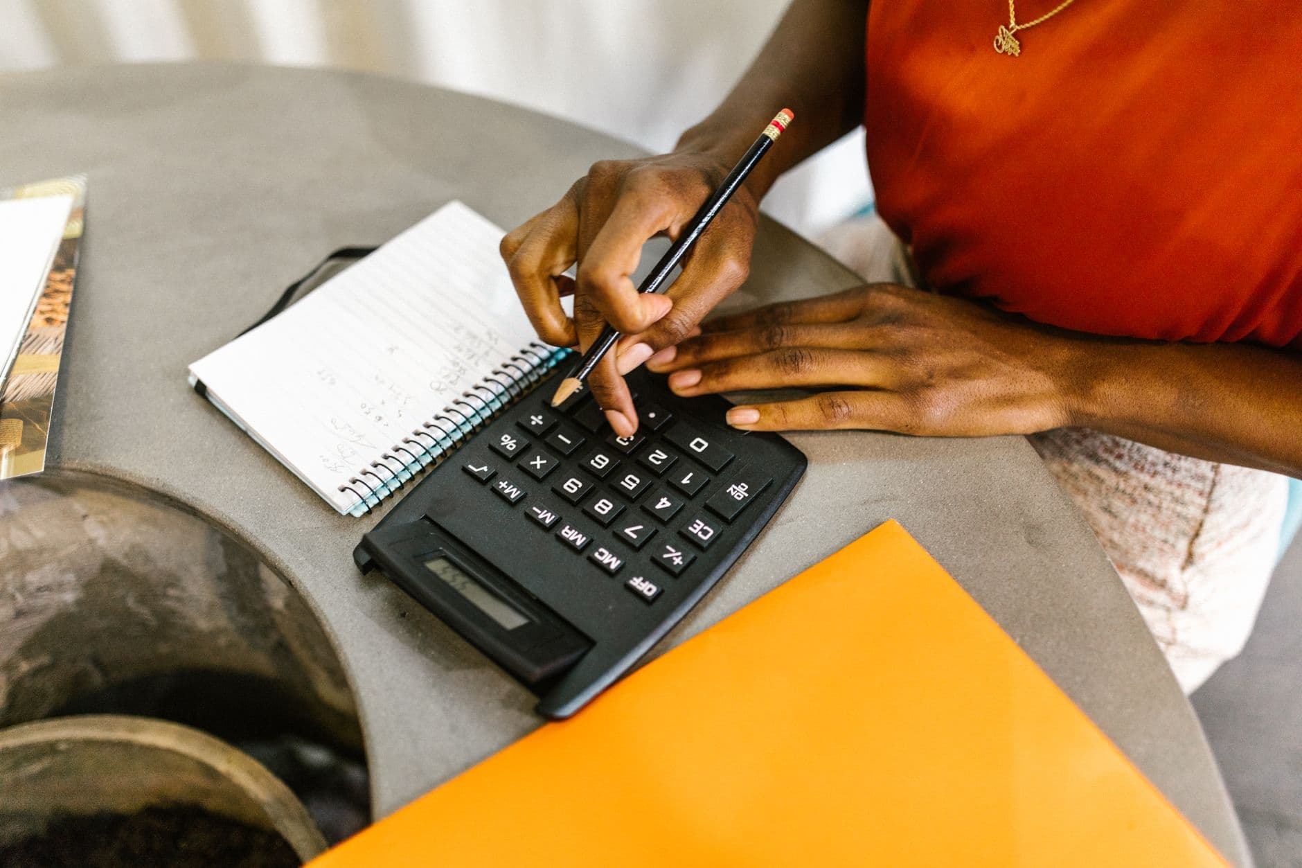 A woman using a calculator and notepad to compare conversion costs